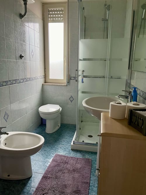Bagno moderno dell'Apartment Tirreno con toilette, lavabo, doccia e pavimento in piastrelle blu