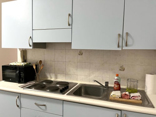 Cucina moderna dell'Apartment Tirreno con mobili bianchi, elettrodomestici in acciaio inox e rivestimento in piastrelle beige