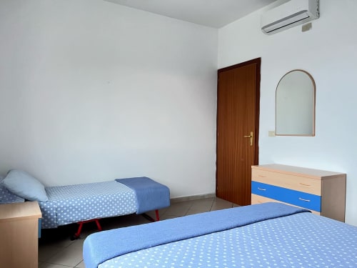 Camera luminosa dell'Apartment Tirreno a Tirrenia con letti gemelli, porta in legno e unità di climatizzazione