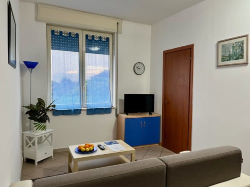 Luminosa sala da soggiorno dell'Apartment Tirreno a Tirrenia con divano grigio, TV, pianta e finestre con vista mare