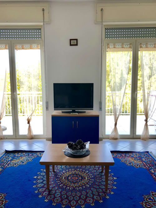 Soggiorno moderno in Apartment Tirreno, Tirrenia con TV, mobili blu, porte-finestre e tappeto decorativo