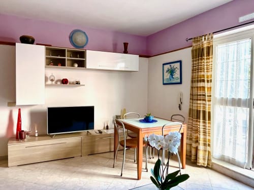 Soggiorno moderno nell'Appartamento Tirreno, Tirrenia con tavolo da pranzo, TV e pareti rosa