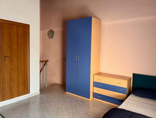 Camera spaziosa dell'Appartamento Tirreno con guardaroba blu, porta in legno e arredi moderni a Tirrenia