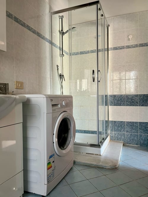 Moderno bagno dell'Apartment Tirreno con lavatrice e doccia in cristallo, Tirrenia
