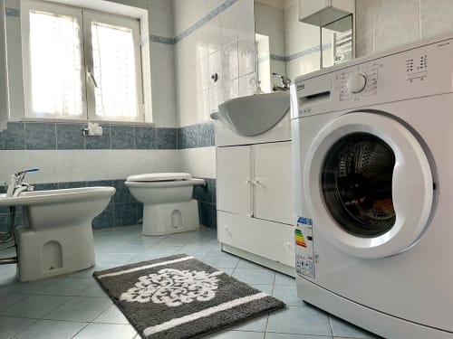 Moderno bagno con lavatrice, wc, lavandino e specchio presso l'Apartment Tirreno a Tirrenia