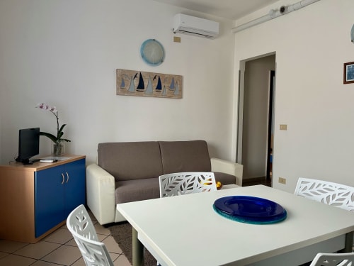 Zona living della moderna camera da letto a Apartment Tirreno a Tirrenia, con divano, tavolo da pranzo e arredamento costiero