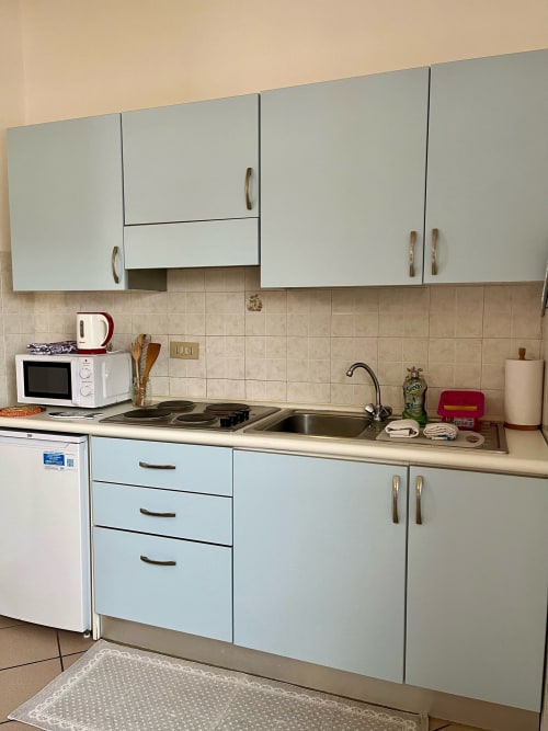 Cucina moderna nell'appartamento di Tirrenia con mobili bianchi, piano cottura elettrico e lavello in acciaio inossidabile