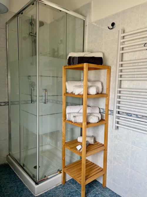 Bagno moderno dell'Apartment Tirreno con doccia in vetro e ripiano in legno con asciugamani e articoli da toilette