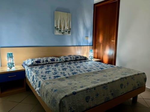 Camera moderna all'Apartment Tirreno a Tirrenia con biancheria blu, testata in legno e arredi contemporanei