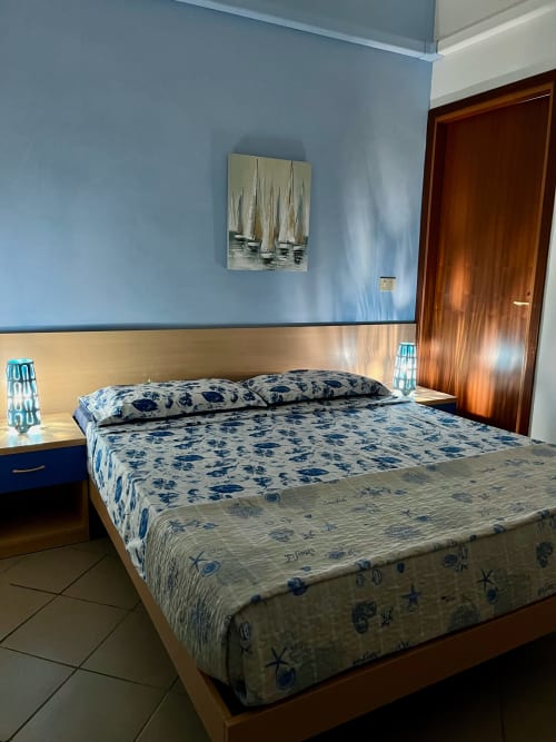 Camera moderna all'Apartment Tirreno in Tirrania con biancheria a tema nautico, letto in legno chiaro e pareti blu.