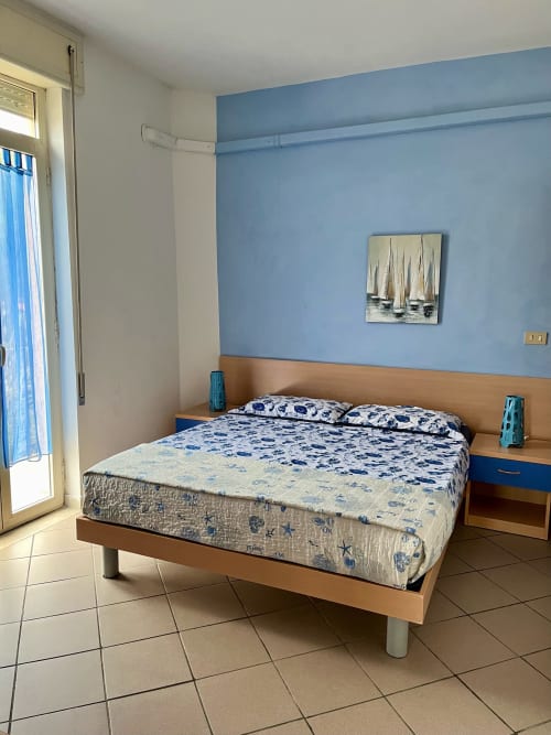 Camera luminosa dell'Apartment Tirreno a Tirrenia con parete blu, letto in legno e arredamento a tema marino.