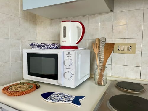 Cucina dell'Apartment Tirreno con microonde, bollitore rosso, utensili da cucina e fornello a Tirrenia