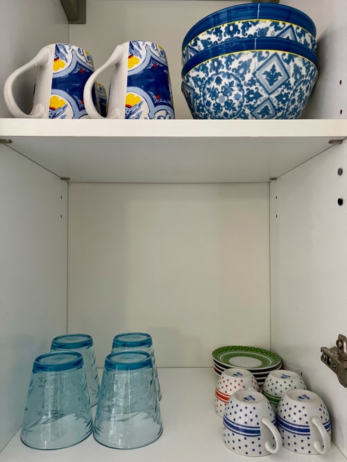 Ripiani di cucina bianchi con stoviglie e bicchieri blu e bianchi all'Apartment Tirreno
