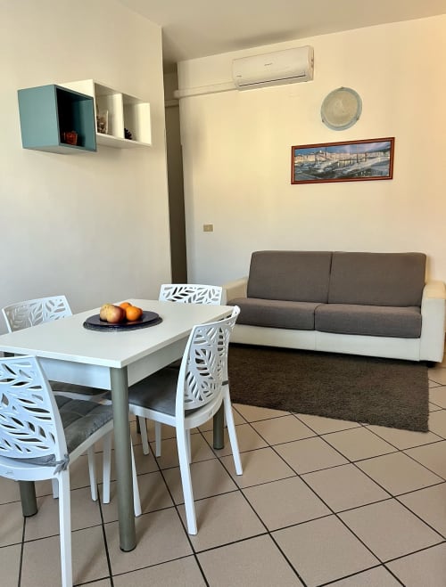 Moderno soggiorno dell'Apartment Tirreno a Tirrenia con tavolo da pranzo, divano e aria condizionata
