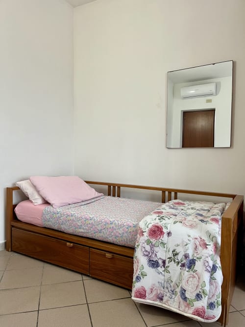 Camera accogliente dell'Apartment Tirreno a Tirrenia con letto singolo in legno, biancheria floreale, specchio e climatizzatore