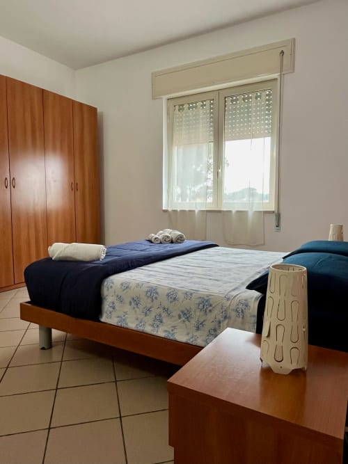 Camera luminosa dell'Apartment Tirreno a Tirrenia con letti gemelli, armadio in legno e grandi finestre