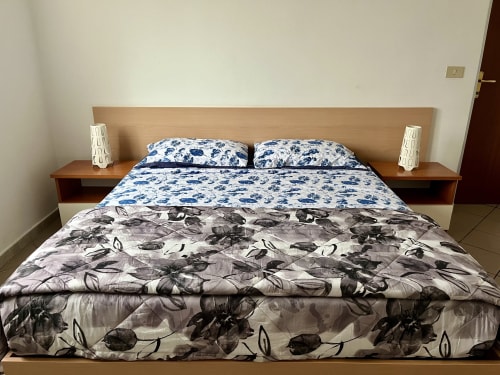 Accogliente camera da letto Standard all'Apartment Tirreno a Tirrenia con biancheria floreale blu, comodini moderni e arredamento bianco