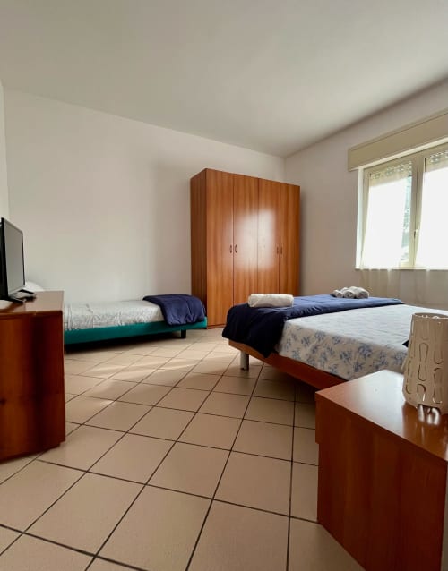 Ampia camera da letto dell'Apartment Tirreno a Tirrenia con due letti, armadio in legno e pavimentazione in ceramica