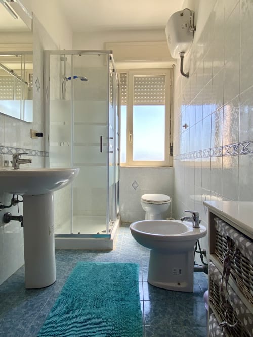 Bagno moderno dell'Apartment Tirreno con lavabo a colonna, bidet, WC e box doccia in vetro