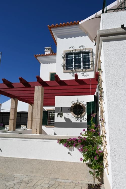Cour de la Villa Sor avec pergola rouge, architecture méditerranéenne blanche et bougainvillées violettes à Ponte de Sor