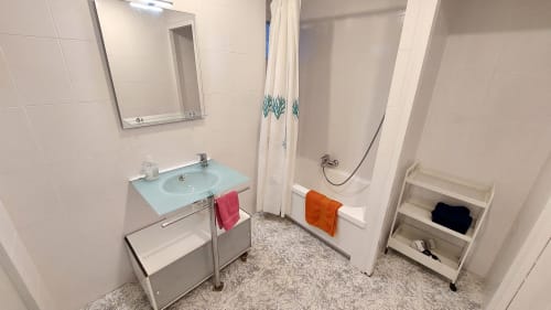 Modern bathroom at Mira Barna Barcelona apartment with glass sink, shower, bathtub, and heated towel rack
