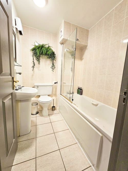 Modern bathroom in Dublin Exchange Suites Liffey Suite with bathtub, shower enclosure, toilet, sink, and hanging plant decor