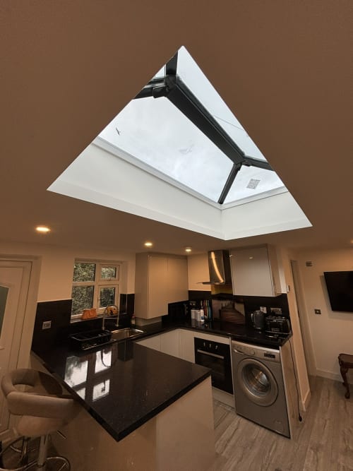 Modern kitchen with black counters, skylight window, and stainless steel appliances in High Wycombe villa