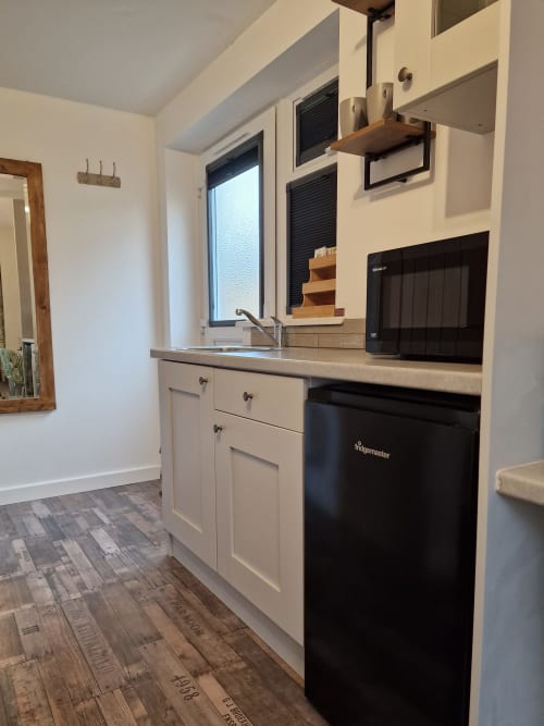 Modern kitchenette at The Little Annex Horsham with cream cabinets, microwave, sink, and wooden flooring