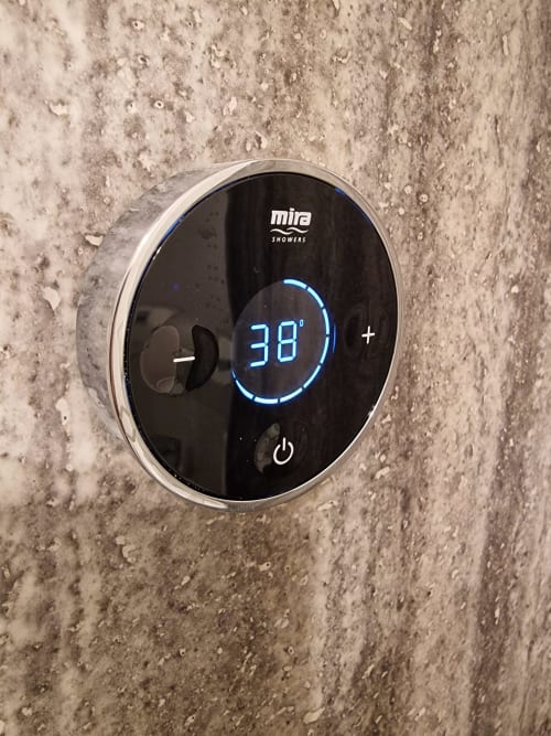 Mira digital shower thermostat displaying 38 degrees on concrete wall at The Little Annex apartment in Horsham