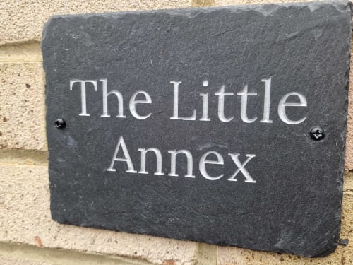 Dark slate nameplate reading 'The Little Annex' mounted on stone wall in Horsham