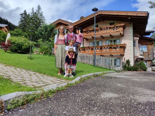 Familie posiert vor dem Residence Rodolon, ein charmantes Alpenchalet mit hölzernen Balkonen in Fontanazzo-Mazzin