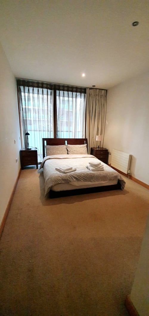 Modern bedroom with king bed, dark wood furniture, river views, and floor-to-ceiling curtains at Dublin Exchange Suites