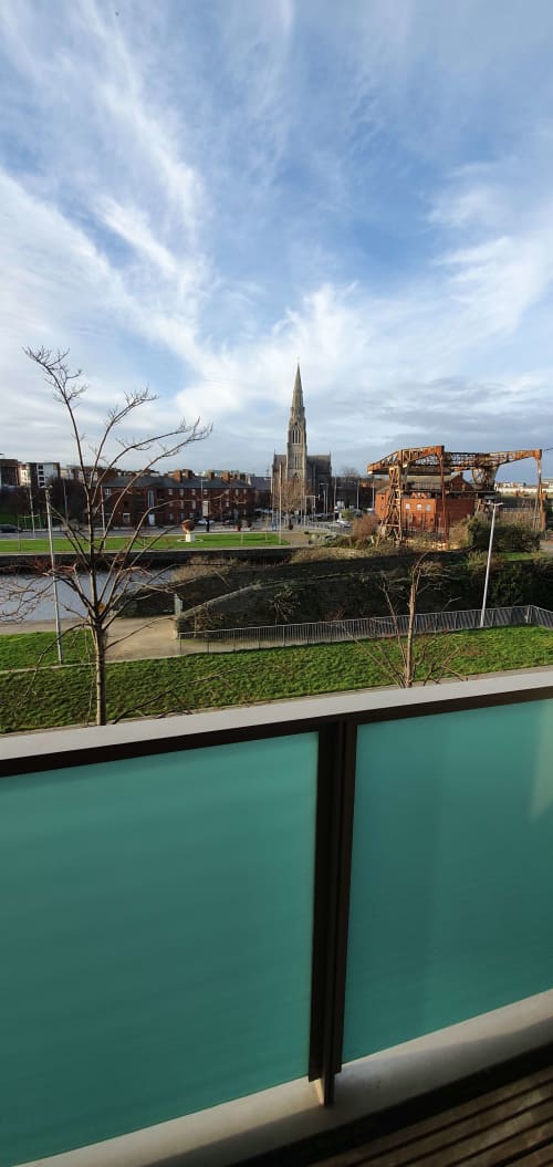River view from Dublin Exchange Suites apartment balcony overlooking green grounds, church spire, and historic architecture