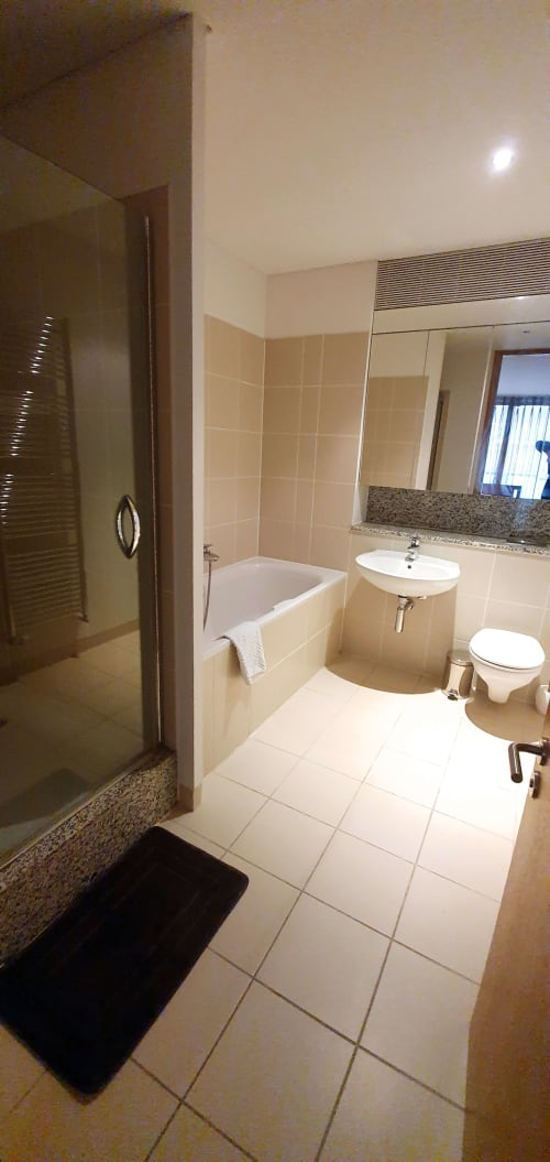 Modern bathroom in Dublin Exchange Suites apartment with bathtub, sink, toilet, shower enclosure, and granite countertops