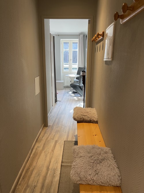 Couloir de la Chambre d'hôtes La Montagnette à Moutiers avec parquet, murs beige et chaises meublées menant à la chambre