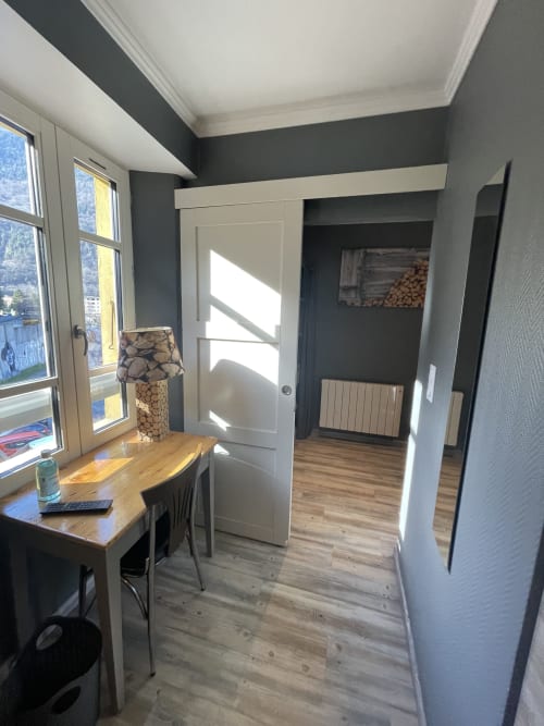 Chambre moderne à La Montagnette à Moutiers avec bureau, vue sur la ville, murs d'accent sombres et porte blanche