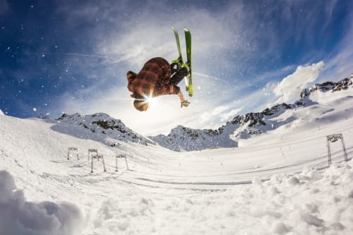 Skifahrer führt Lufttrick über verschneiten Hängen bei Mazzin in den italienischen Alpen auf