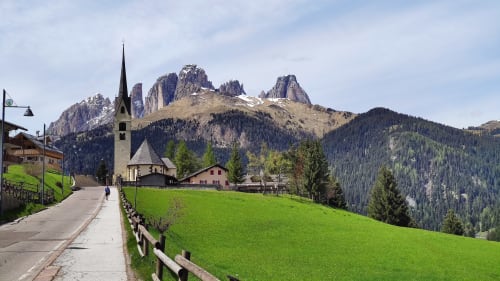 Alpenkirche mit Dolomitengipfeln, grüne Wiesen bei Residence Rodolon, Mazzin, Italien