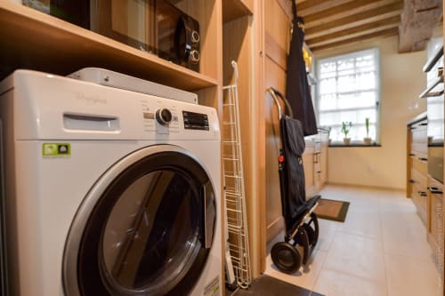 Modern laundry room in Honfleur cottage with Whirlpool washing machine dryer and storage shelves