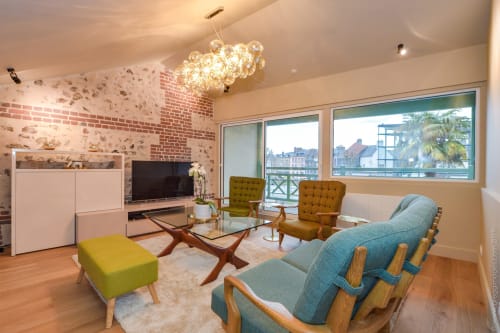 Stylish living room with brick wall, mid-century furniture, and city view balcony at boutique hotel in Honfleur