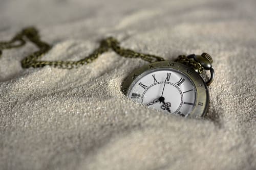 Vintage watch in the sand illustrating arrival times
