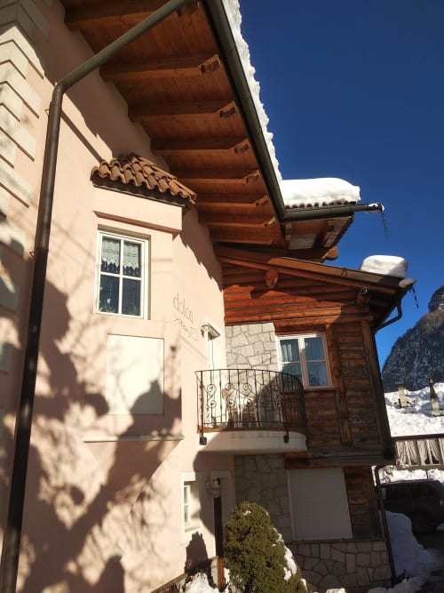 Residence Rodolon Greppa Apartment exterior in snowy Mazzin, Italy with wooden pergola and mountain views