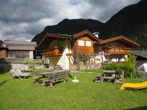 Residence Rodolon Berghotel mit hölzernen Chalets, Bergblick und grüner Rasenfläche zum Entspannen in Mazzin, Italien