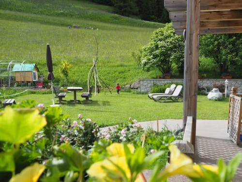 Garten der Residenza Rodolon mit Liegestühlen, Picknicktisch und Blick auf Bergwiesen in Mazzin, Italien