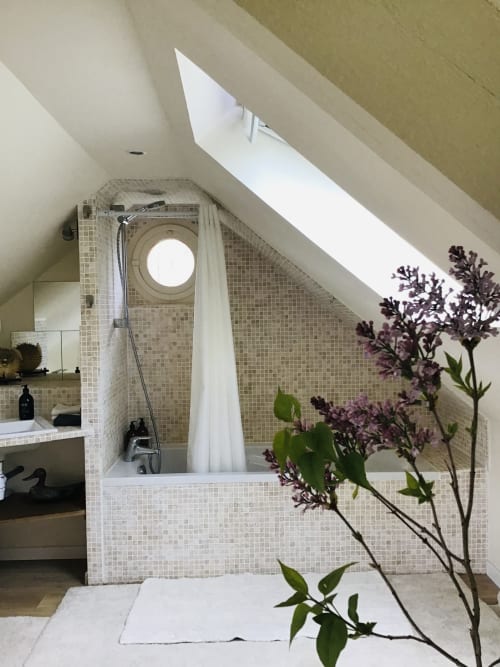 Modern attic bathroom at Clairseine B&B cottage with skylight, tiled shower enclosure, and purple flowers in