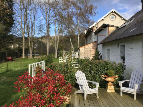 Clairseine cottage terrace with red flowers, white Adirondack chairs, and river views at Tournedos-sur-Seine
