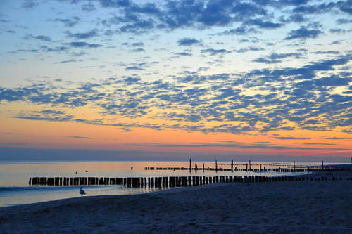 Sunset at Chipiona beach with wooden pier and person wading, Bungalow Buda Beach