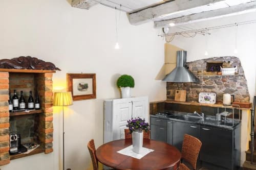 Cuisine-salle à manger de l'appartement Le Viole à Dimora i Manichei, Monforte d'Alba, avec table ronde et électroménagers noirs
