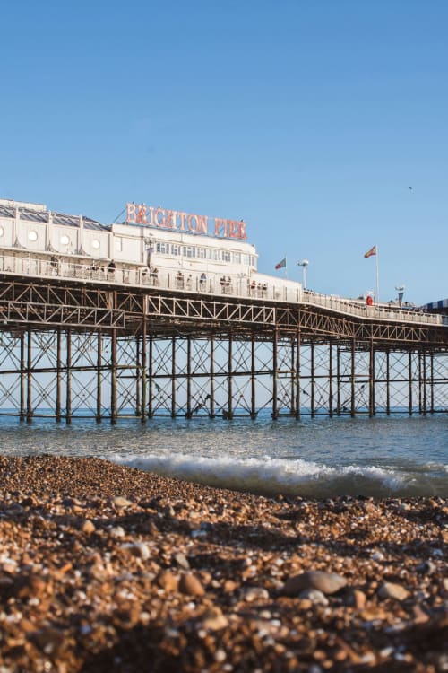 Brighton Pier extending into the sea with pebble beach and clear blue sky, near The Little Annex hotel in Horsham