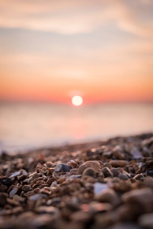 Sunset over pebbled beach with golden sky, near The Little Annex in Horsham